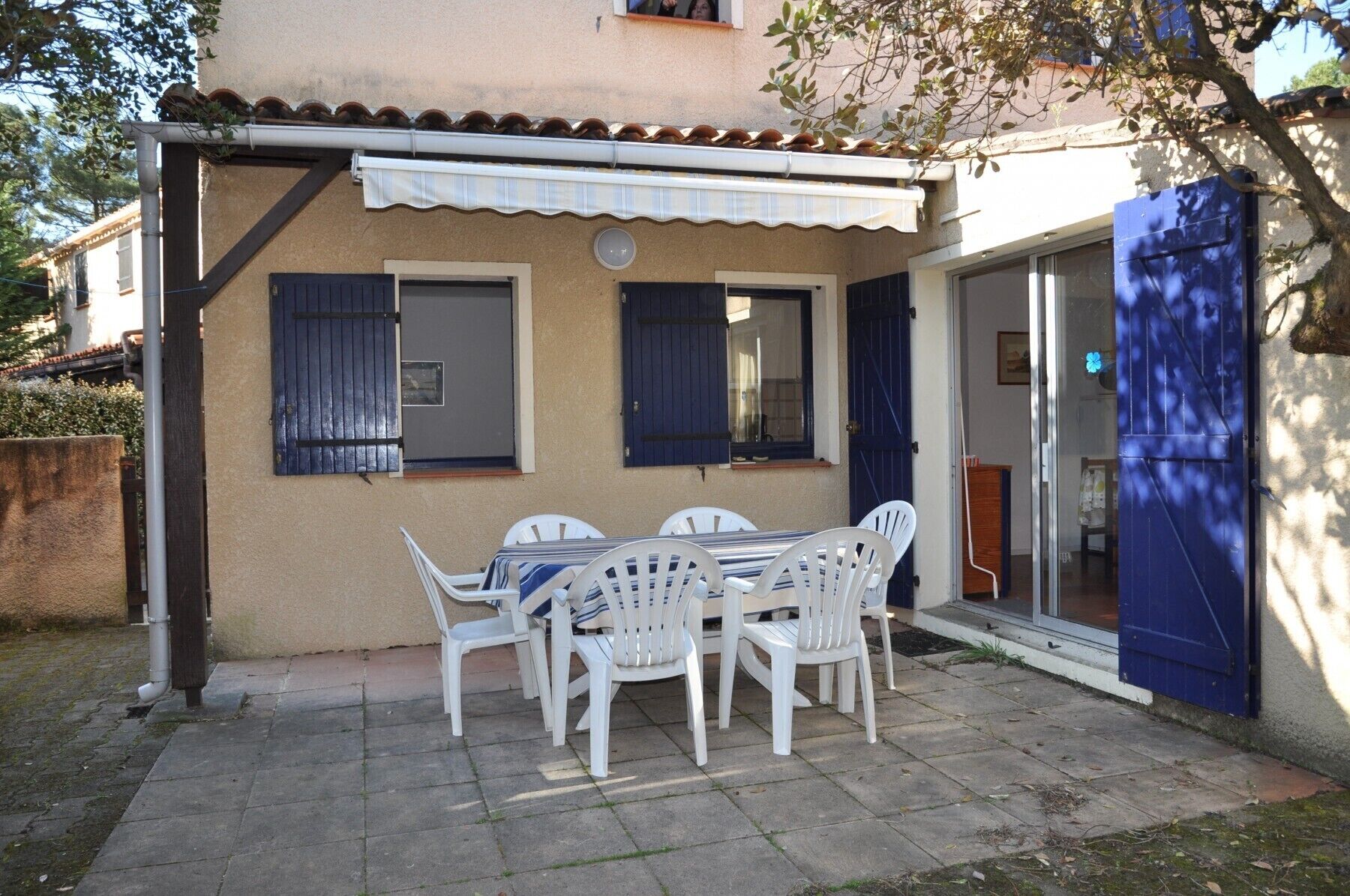 A patio with a table and chairs, a covered area, and a blue door.
