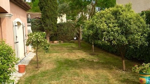 A well-maintained garden with a variety of trees and shrubs, a clear pathway, and a building with a tiled roof and a door. - Beautiful, quiet villa in a beautiful village in the south of France (La Colle-sur-Loup)
