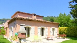 A two-story house with a tiled roof, a patio with outdoor furniture, and a well-maintained lawn. - Beautiful, quiet villa in a beautiful village in the south of France (La Colle-sur-Loup)