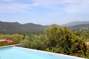 Une piscine avec vue sur les montagnes et la verdure.