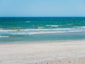 A beach with clear blue water and a sandy shore.