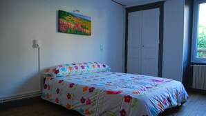 A bedroom with a bed, a painting on the wall, and a window. - Village center, Village house for 4 people (Florac)