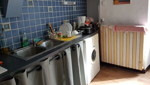 A kitchen with blue tiles, a washing machine, and a radiator. - Village center, Village house for 4 people (Florac)
