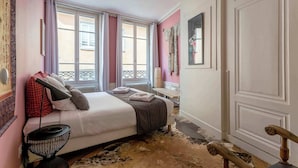 A bedroom with a bed, a bedside table, a lamp, and a window with curtains.