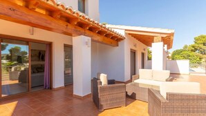 A covered outdoor patio with wicker furniture and a pergola.