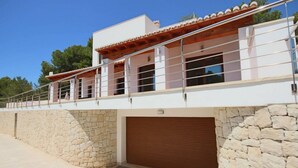 A modern building with a stone facade, a wooden balcony, and a garage door.