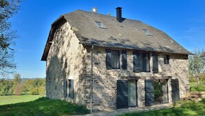 Ein Haus aus Stein mit einem geneigten Dach, mehreren Fenstern und einem Schornstein.