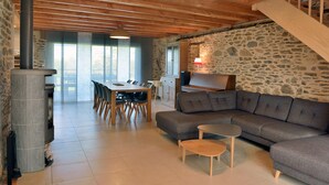 Ein modernes Wohnzimmer mit Steinwand, grauem Sofa, Holzesstisch und einer Treppe.