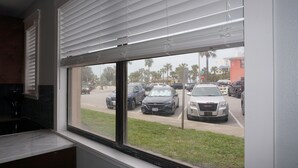 A view from inside a room with a large window overlooking a parking lot with several cars.