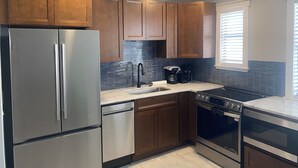 A modern kitchen with wooden cabinets, stainless steel appliances, and a tiled backsplash.