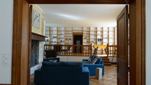 Een woonkamer met een open haard, een televisie en een boekenkast.