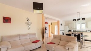 Een moderne woonkamer met twee beige banken, een salontafel en een keuken op de achtergrond.