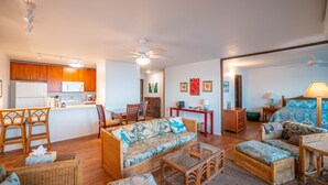 A compact living space with a kitchenette, a dining area, a sofa set, and a bedroom.