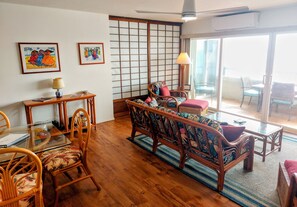Un salón japonés tradicional con esteras de tatami, una mesa de madera baja y un sofá con cojines de colores.