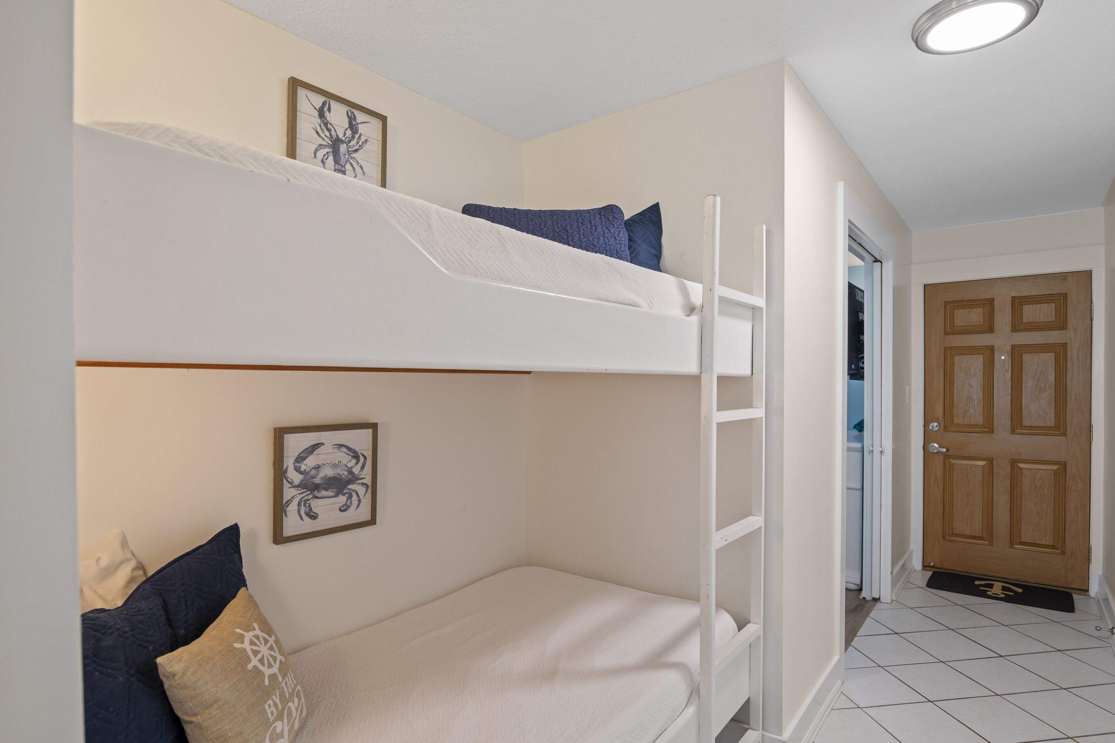 Habitación con literas, una escalera, una puerta y un cuadro en la pared.