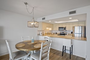 A modern kitchen with white cabinets, a wooden island, and a dining area with a round table and chairs. - 204- Find your perfect BEACH vacation at Destin Beach Club (Destin)