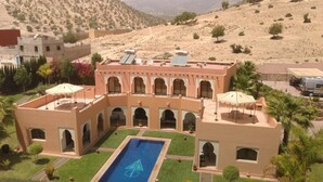Un edificio tradizionale con un cortile centrale, una piscina e antenne paraboliche sul tetto.