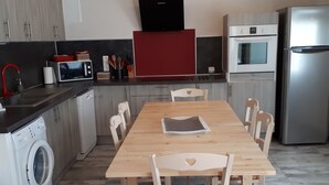 Una cocina moderna con una mesa de madera, sillas, lavadora, microondas y refrigerador.
