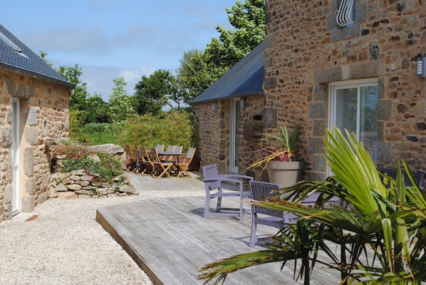 A stone building with a wooden deck, outdoor seating, and a stone wall.