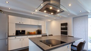 Een moderne keuken met witte kasten, een centraal eiland met kookplaat en een inbouwoven.