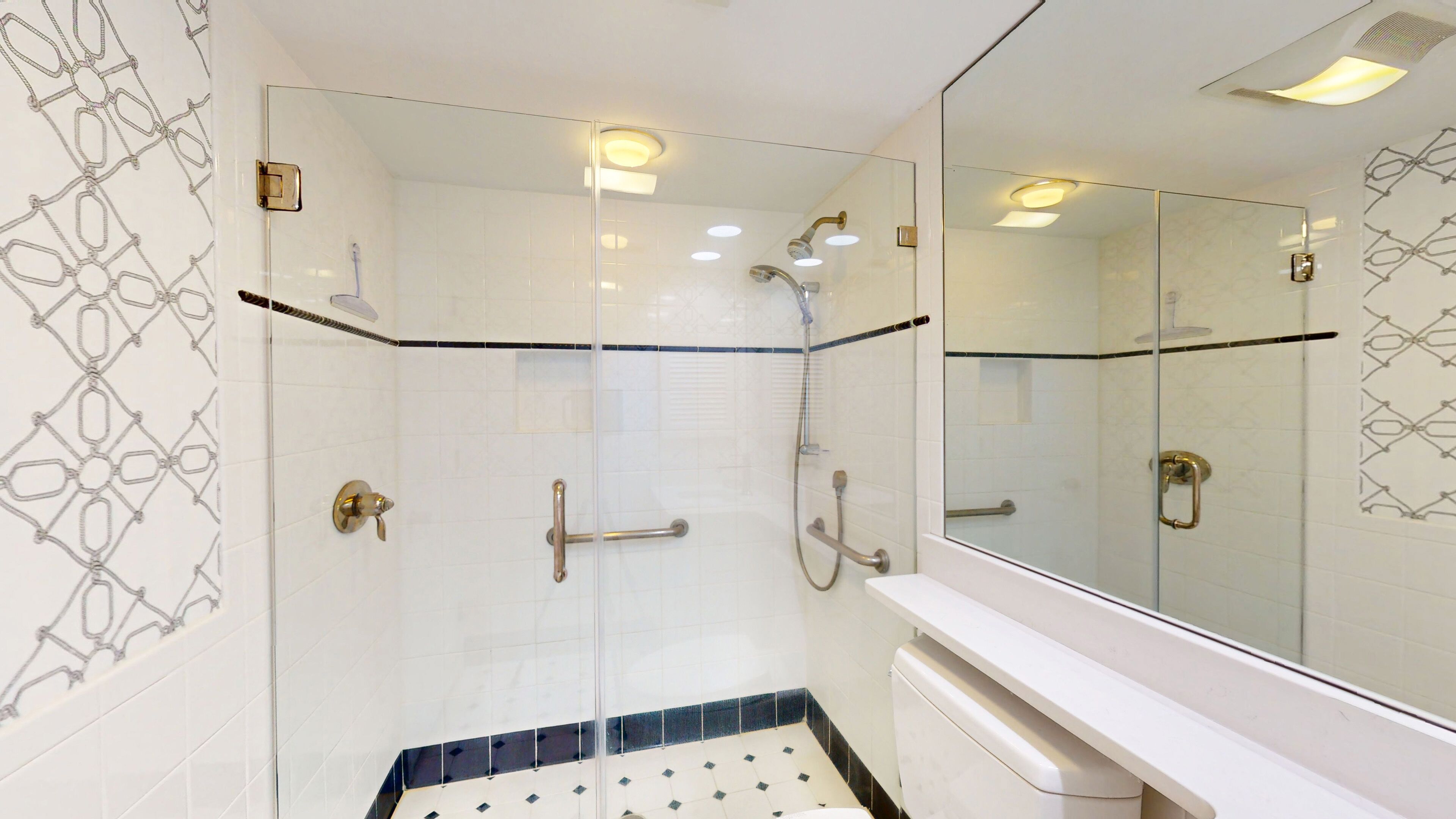 A modern bathroom with a glass-enclosed shower, a white sink, and a large mirror.