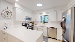 Una cocina moderna con armarios blancos, electrodomésticos de acero inoxidable y una isla central.