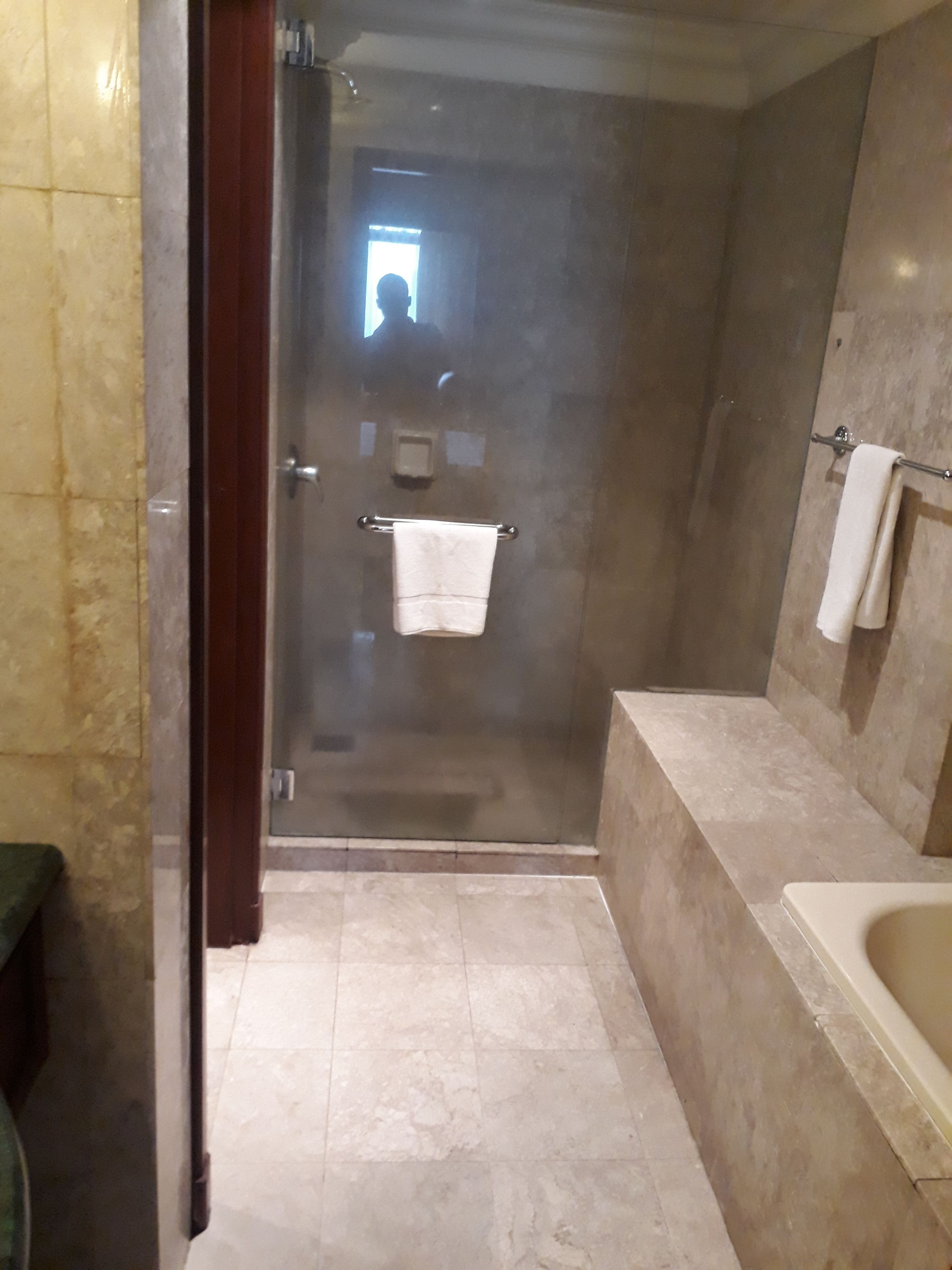A bathroom with a glass shower enclosure, a bathtub, and a towel rack.