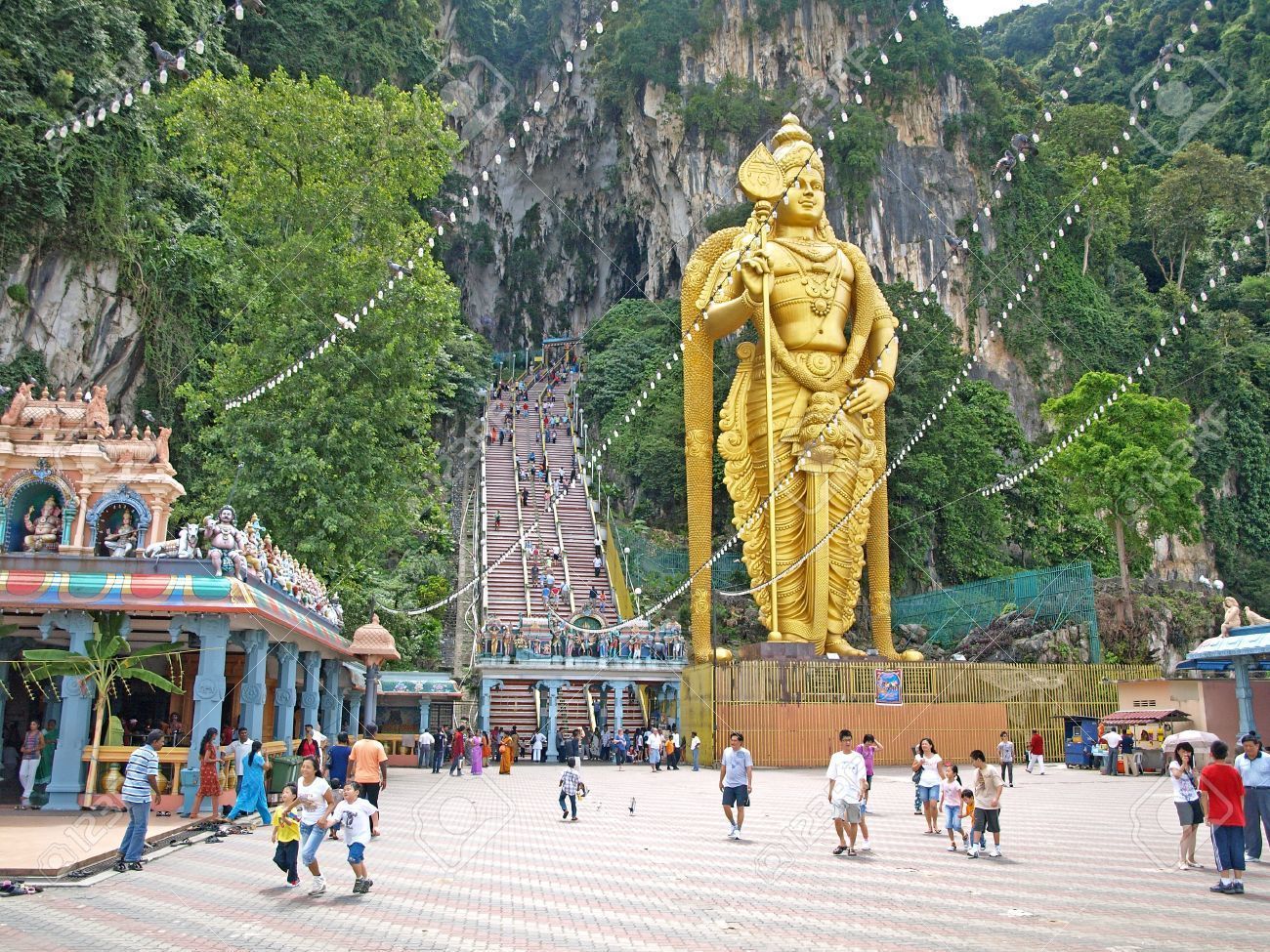 A large golden statue in a temple complex with a staircase leading to a temple.
