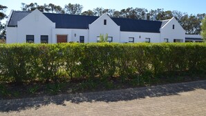 A modern white building with a dark roof, surrounded by a well-maintained hedge. - Cape Town Luxury  Self Catering Home in a Working Wine Farm - Family Friendly (Cape Town)