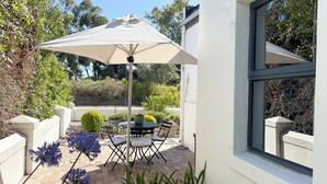 An outdoor patio with a table and chairs, a white umbrella, and potted plants. - Cape Town Luxury  Self Catering Home in a Working Wine Farm - Family Friendly (Cape Town)