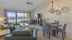 Un vaste salon avec balcon, un coin repas et un ventilateur de plafond.