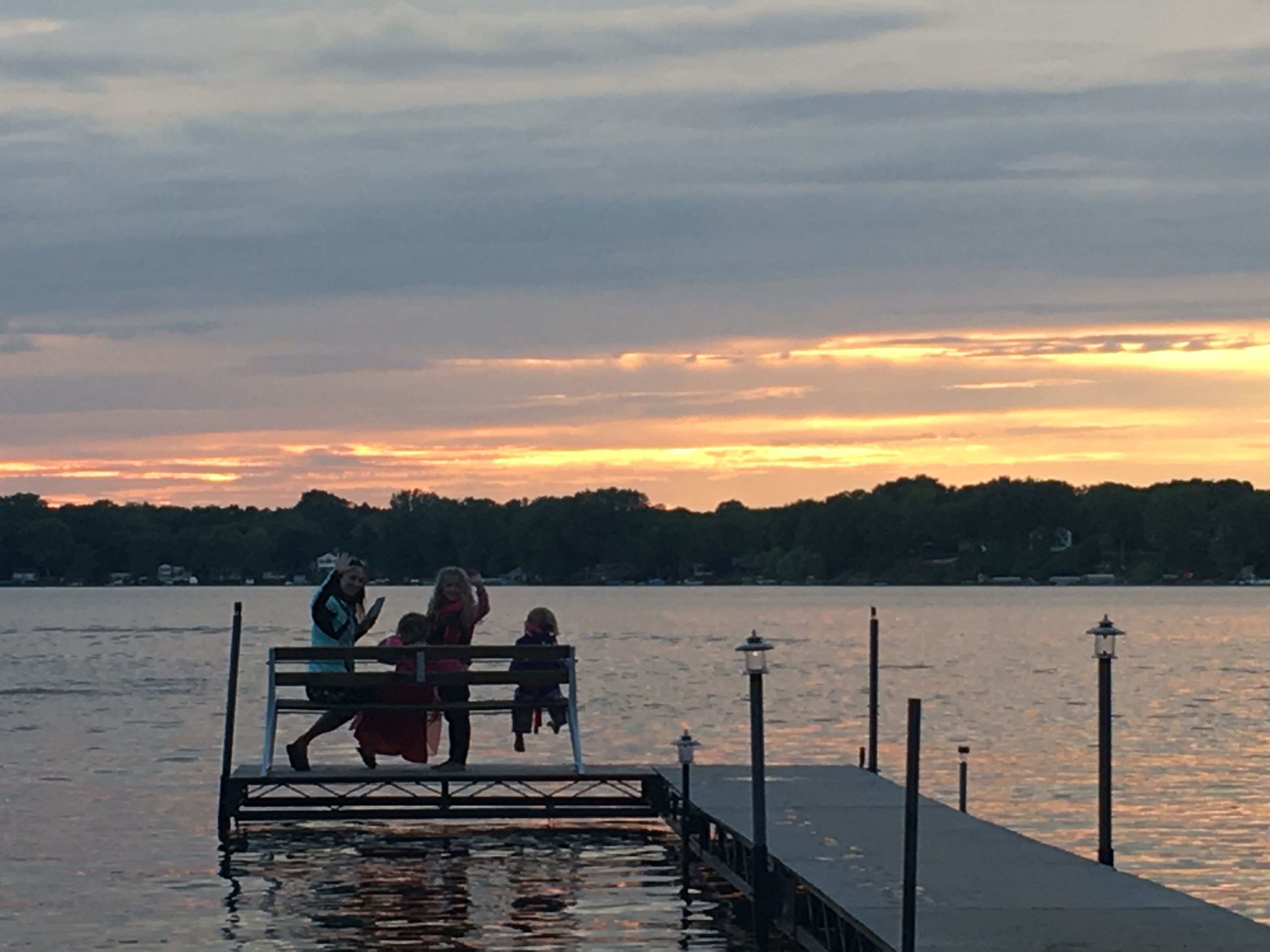 A pier extending into a body of water with a sunset in the background.