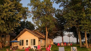 A house with a front yard, a sandy area with beach chairs, and a small pool. - Hamptons style Lake house on Sunset point. With water on both the east and west! (Lindstrom)