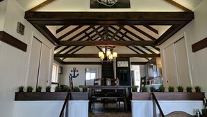 A spacious interior with a high ceiling, wooden beams, and a central staircase. - Hamptons style Lake house on Sunset point. With water on both the east and west! (Lindstrom)