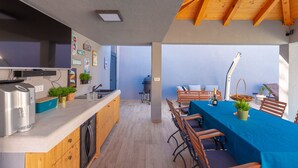 A modern kitchen with a built-in oven and a dining area with a table set for two. - Villa Vikor with large private swimming pool and jacuzzi..... (Dubrovnik)