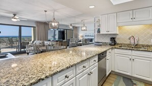 Una cocina moderna con encimeras de granito, armarios blancos y vista al océano.