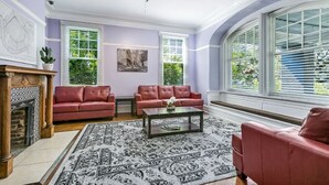 A living room with two red sofas, a coffee table, and a fireplace. - Charming Studio | Central NOLA Vibes (New Orleans)