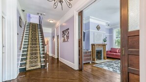 A hallway with a wooden staircase, a fireplace, and a red sofa. - Charming Studio | Central NOLA Vibes (New Orleans)