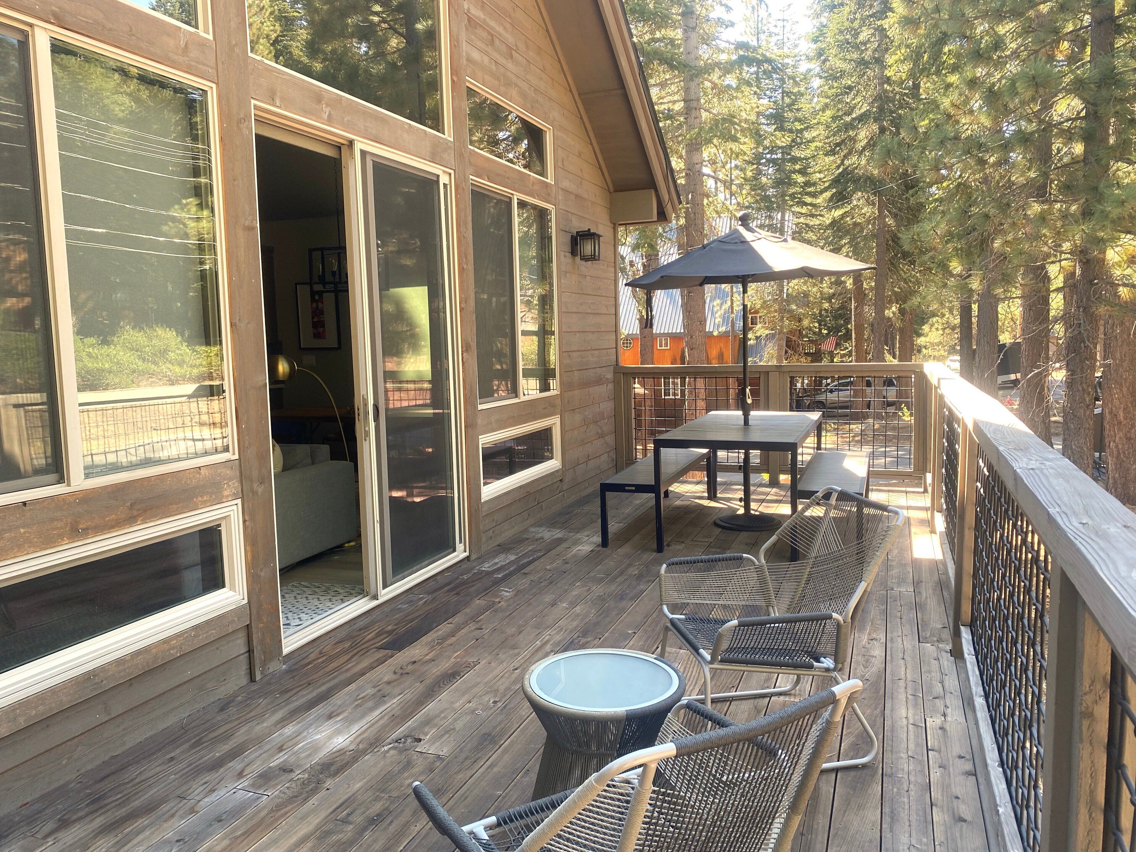 A wooden deck with outdoor furniture, including a table and chairs, and a covered area with a table and chairs.