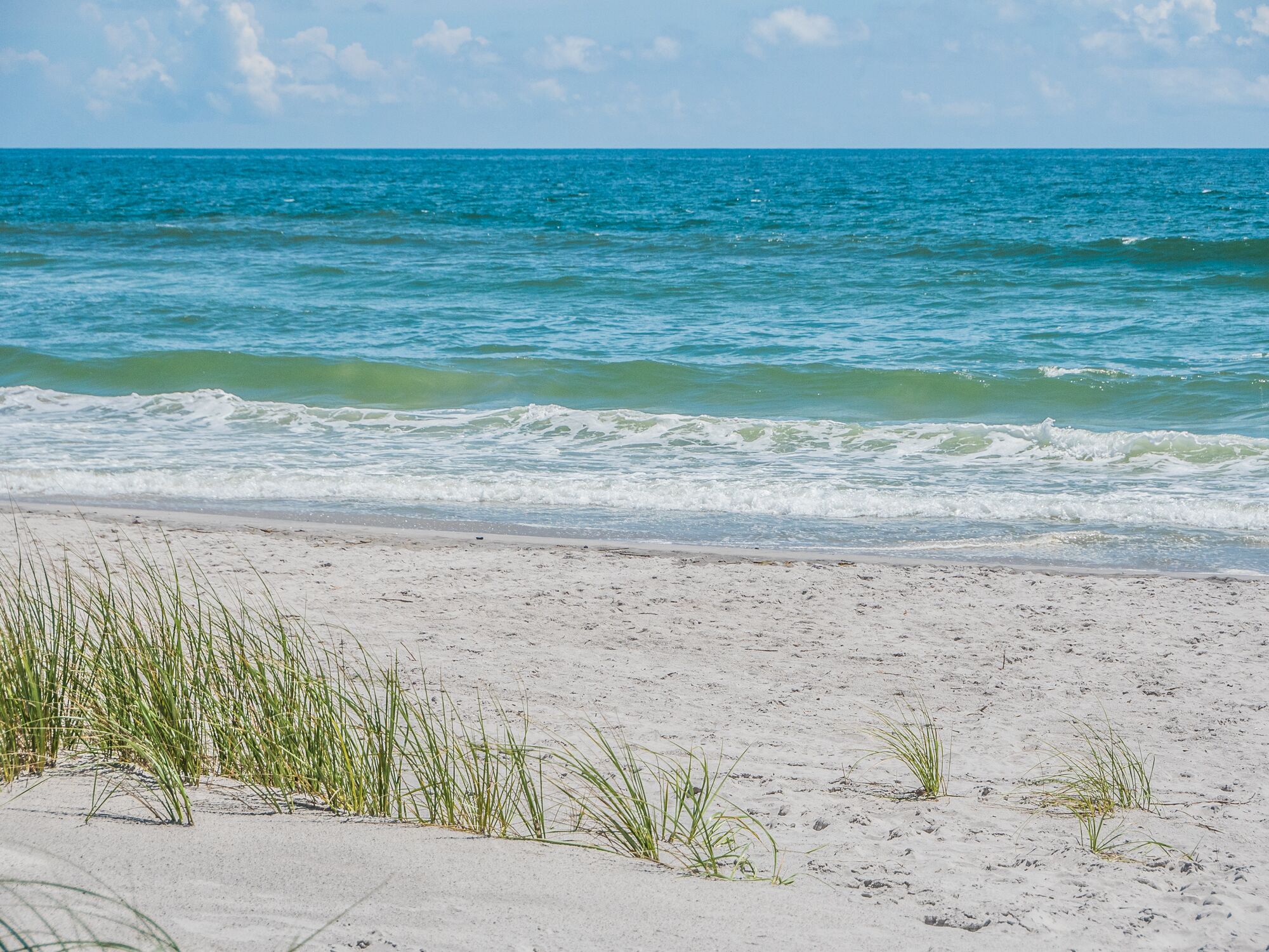 Ein Strand mit klarem, blauem Wasser und weißem Sand.
