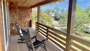 Eine Holzveranda mit einer Ziegelwand und Blick auf Häuser und Bäume.