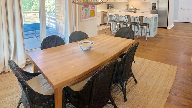 Eine moderne Küche mit weißen Schränken, einem Edelstahl-Kühlschrank und einem Essbereich mit Holztisch und Korbstühlen.