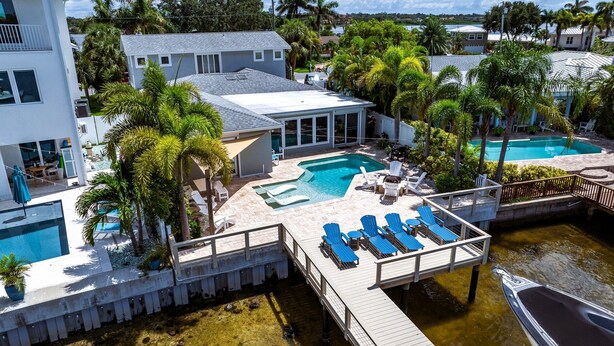 A residential property with a swimming pool, lounge chairs, and a dock. - Ocean Dreaming: Waterfront Home with Heated Pool, New Dock and Amazing Sunsets! (Indian Rocks Beach)