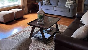 A cozy living room with a grey sofa, a coffee table, and a patterned rug.