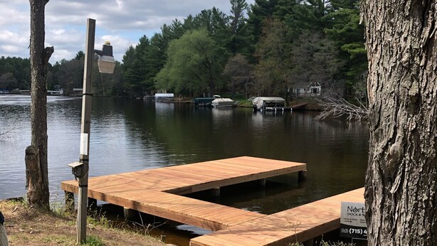A dock with a sign for 'Nort Dock & Dock & Decks' and a wooden pier extending into a lake.