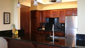 Een moderne keuken met houten kastjes, roestvrijstalen apparatuur en een zwart aanrecht.