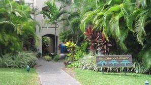 Stroll through the serene garden to the Sandalwood Tower, surrounded by lush tropical plants and palm trees.