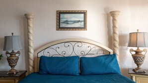 Une chambre à coucher comprenant un lit, deux tables de chevet, une lampe, un tableau encadré et un mur décoratif.