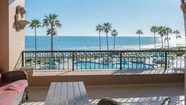 Un balcon avec vue sur une piscine et une plage.