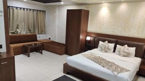 Ein modernes Hotelzimmer mit einem großen Bett, einer Couch, einem kleinen Tisch und einem Kleiderschrank.